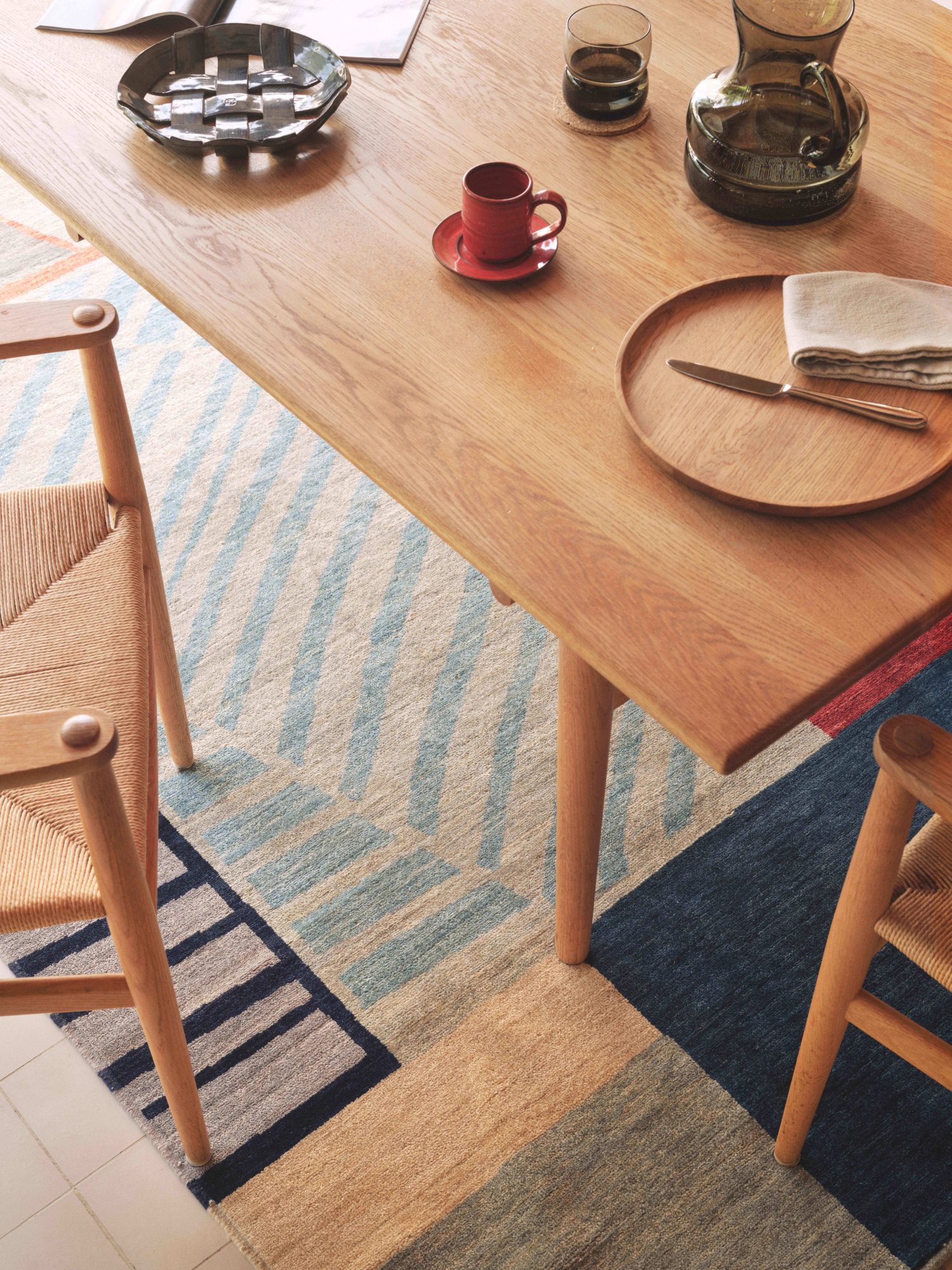 The textural Pleat hand knotted rug from the Verso collection features intersecting lines in blue, gray and red tones.
